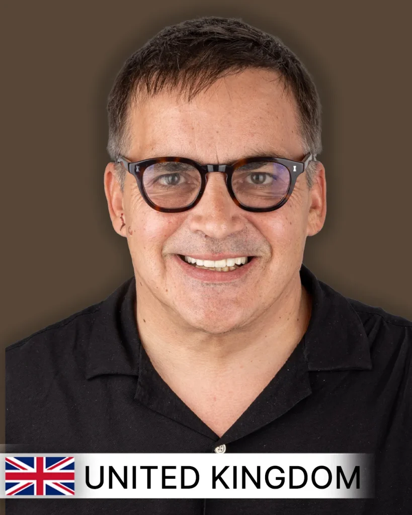 Close-up of a smiling patient, likely in their 30s or 40s, with visibly whiter, straighter, and evenly aligned teeth, suggesting a successful smile makeover. The background is softly blurred, possibly a dental clinic setting in the United Kingdom.
