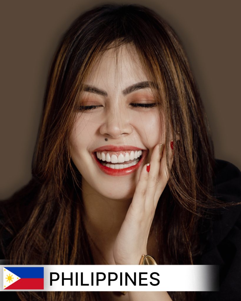 Close-up of a smiling patient, likely in their 20s or 30s, proudly displaying visibly whiter, straighter, and beautifully aligned teeth after a successful smile makeover. The background is softly blurred, hinting at a modern dental clinic setting in the Philippines.